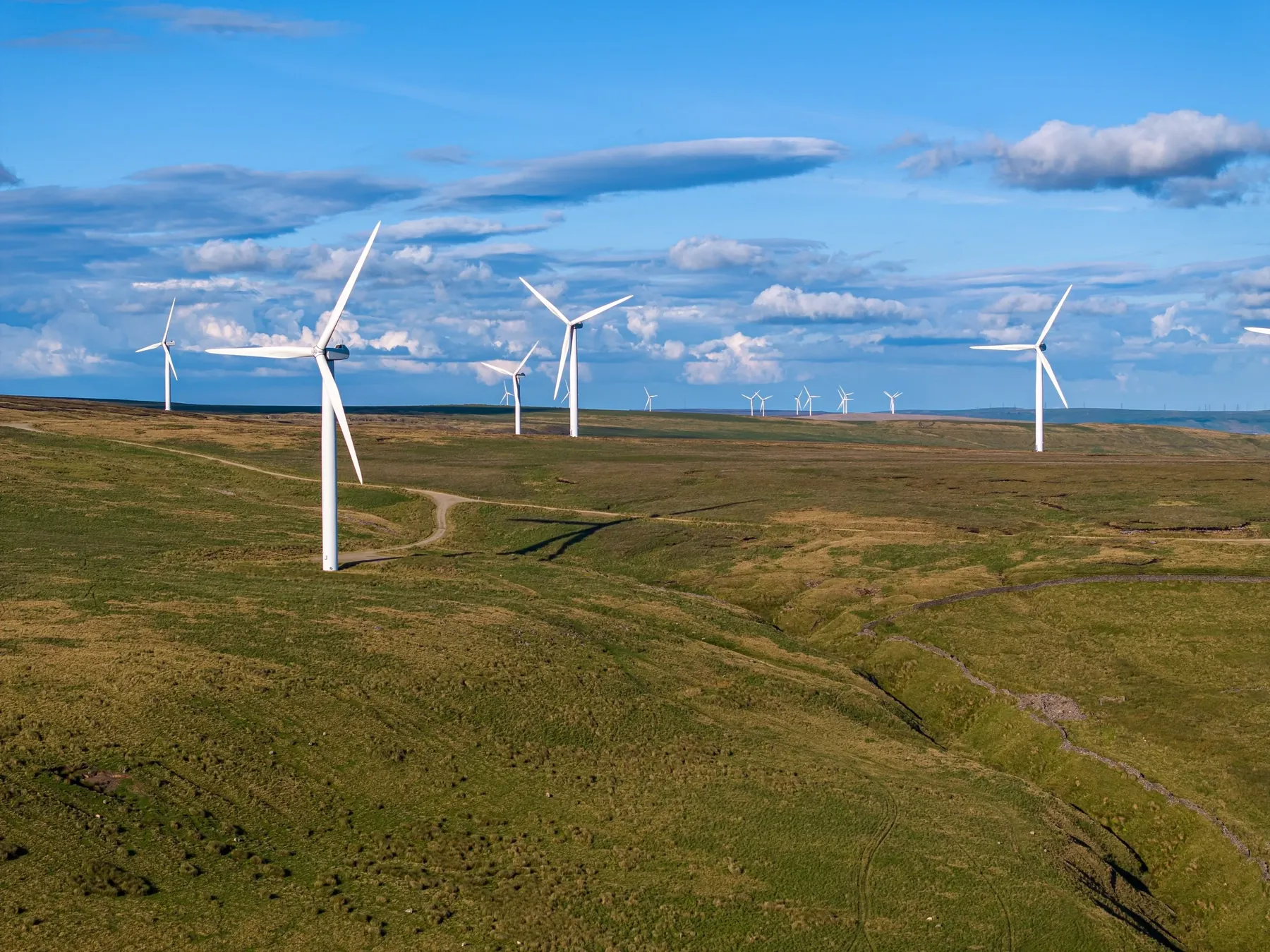 Wind turbines on a green upland under a blue sky